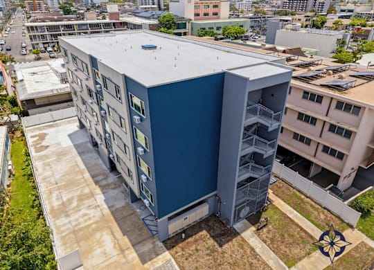 A blue building with a white roof is surrounded by other buildings.