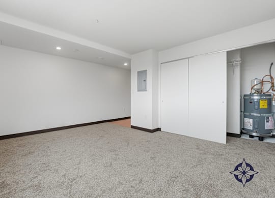 A room with a carpeted floor, a white door, and a white wall with a window.