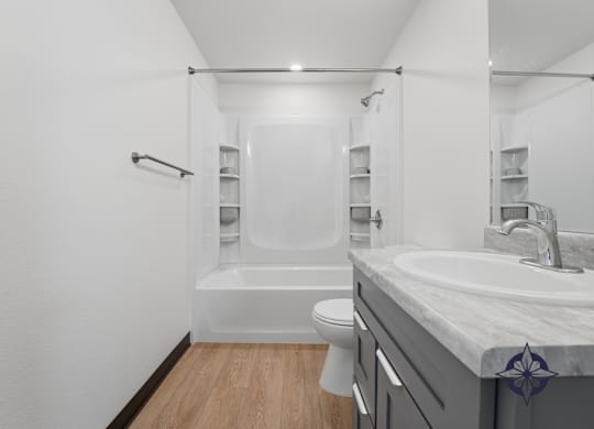 A bathroom with a white tub, sink, and toilet.
