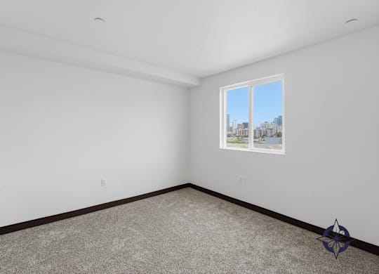 A room with a carpeted floor and a window showing a cityscape outside.