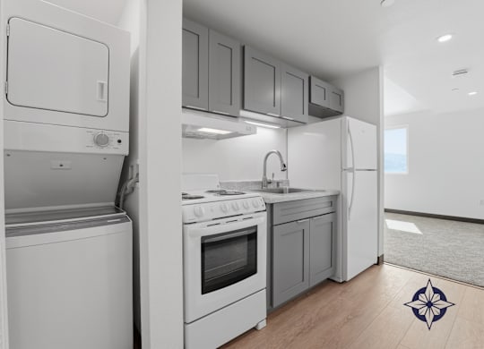 A modern kitchen with white appliances and wooden flooring.