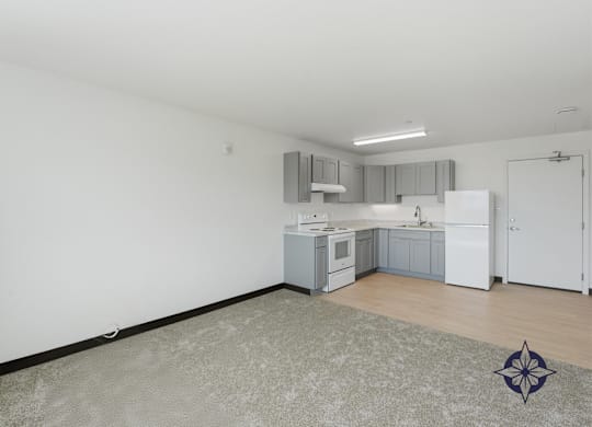 A kitchen with white cabinets and a white fridge is shown.