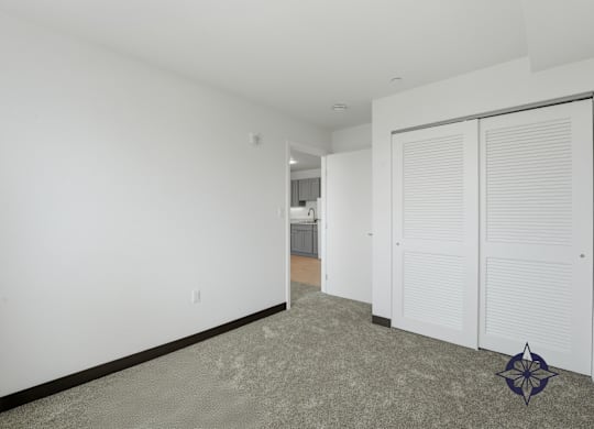 A room with a carpeted floor and a white wall with a door and a window.