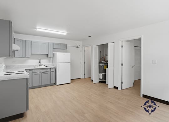A kitchen with a white fridge and wooden floors.
