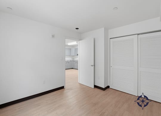 A room with white walls and wooden flooring with a white door and a white wardrobe with a star design on the floor.