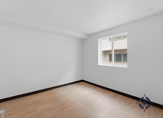 A room with a window and a wooden floor.