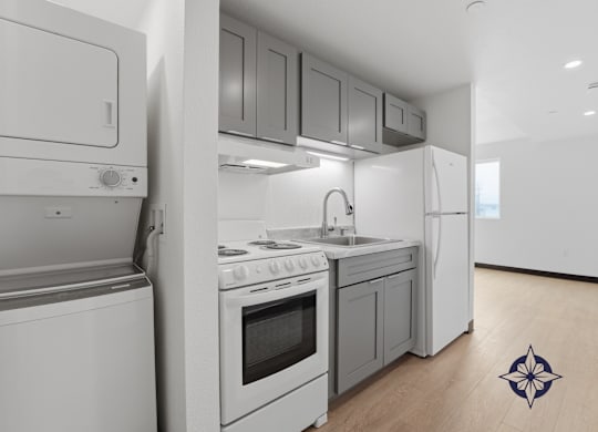 A modern kitchen with white appliances and wooden flooring.