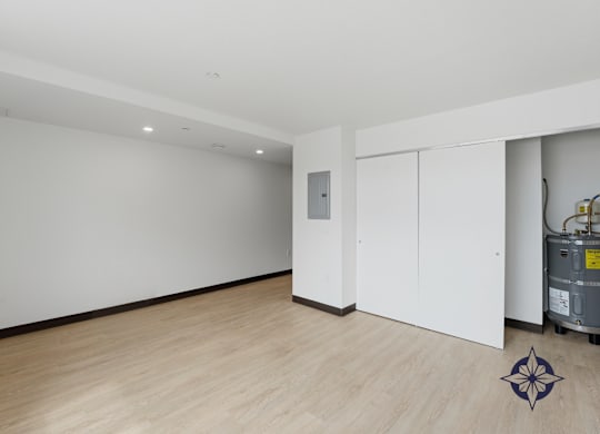 A room with a wooden floor and a white wall with a door and a window.