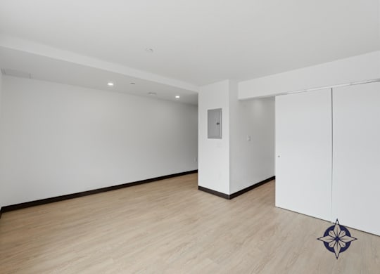 A room with a wooden floor and a white wall with a door.