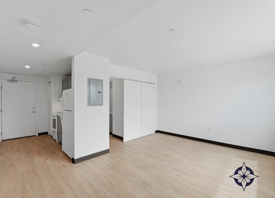 A room with a white wall and a wooden floor with a compass design on it.