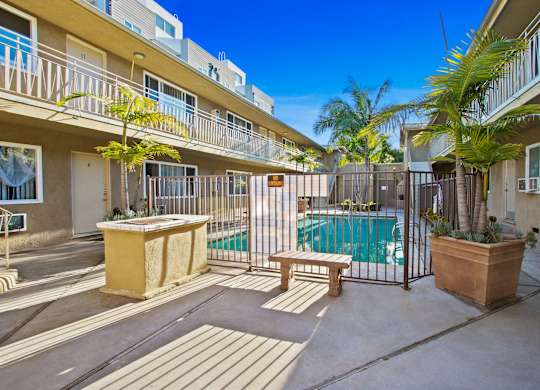 A sunny day at a poolside with a bench and a table.