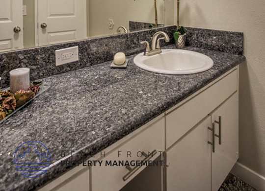 A bathroom with a granite countertop and a white sink.