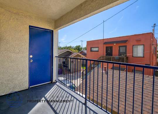 A balcony with a blue door and a black railing.