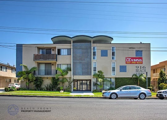 A modern apartment building with a leasing sign in front.