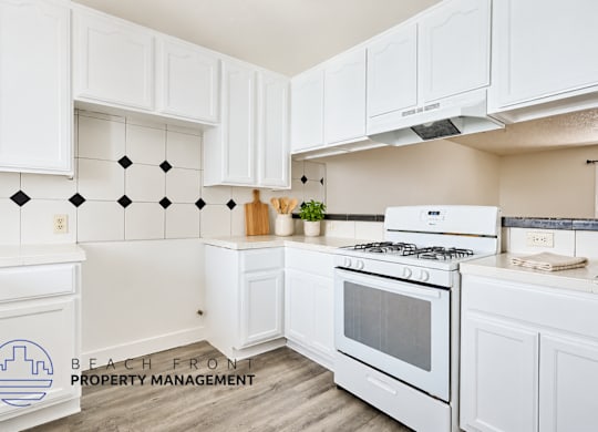 A kitchen with white cabinets and a white stove top oven.