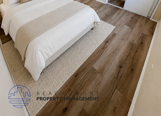 A bedroom with a large bed and a wooden floor.