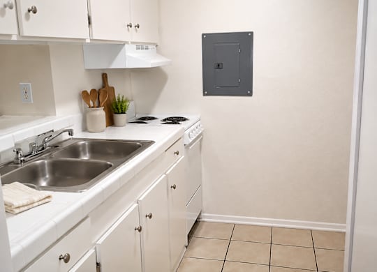 A kitchen with white cabinets and a stove top oven.