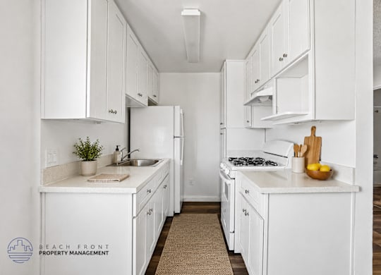 A kitchen with white cabinets and appliances, a sink, and a cutting board with lemons on the counter.