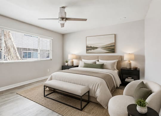A bedroom with a large bed, a ceiling fan, and a window with blinds.