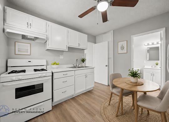 A kitchen with a white stove, cabinets, and a ceiling fan.