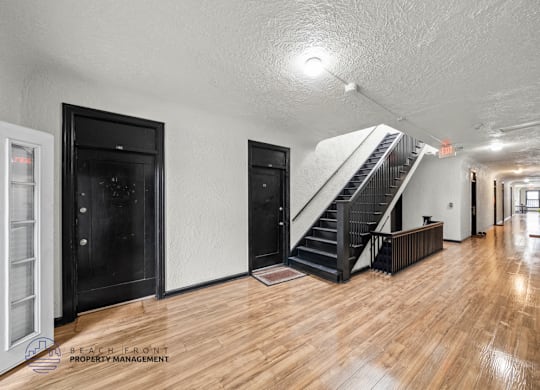A spacious room with wooden floors and a staircase leading to another level.