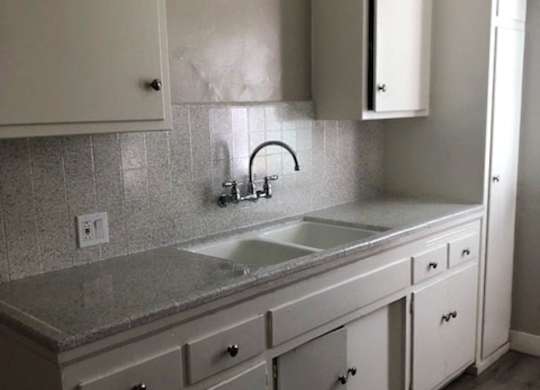 A kitchen with white cabinets and a granite countertop.