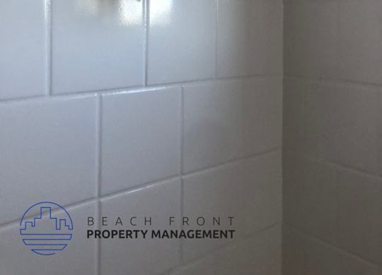 A shower head mounted on a white tiled wall.