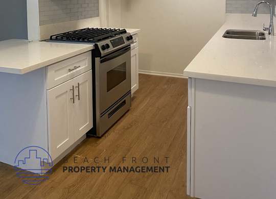 A kitchen with white cabinets and a stove top oven.