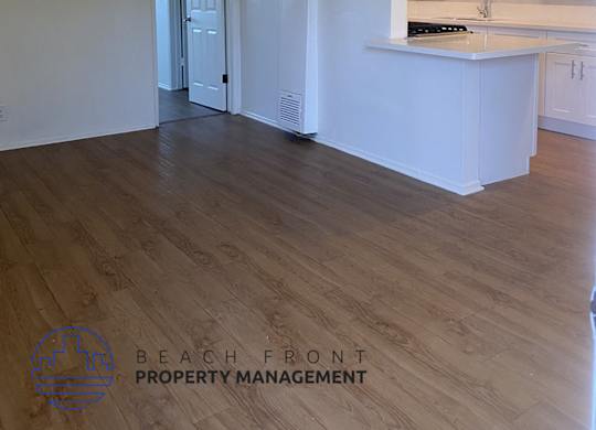 an empty kitchen with white cabinets and a wood floor