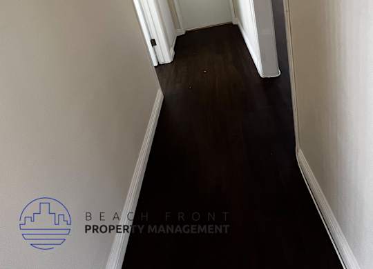 A hallway with white walls and a wooden floor.