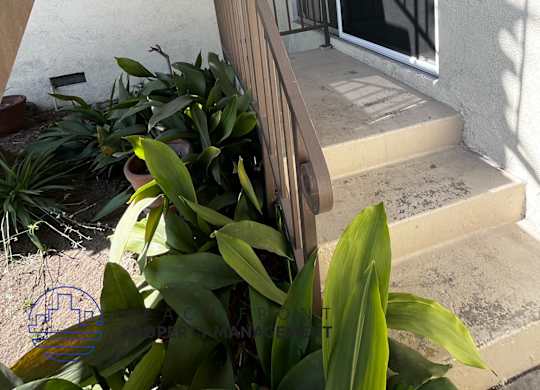 A balcony with a railing and steps leading up to a glass door.