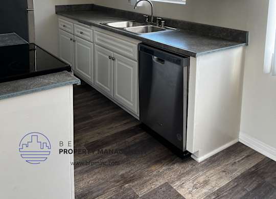 A kitchen with white cabinets and a black counter top.