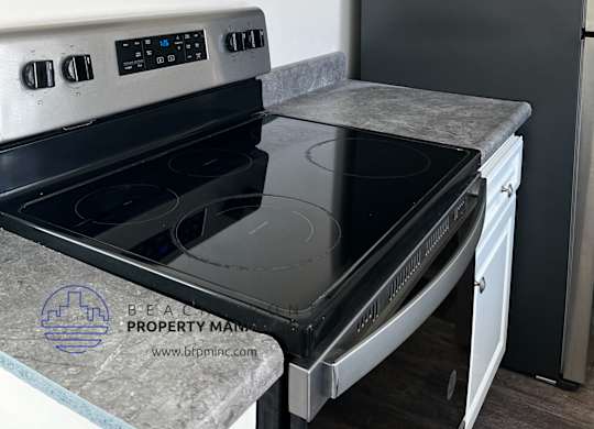 A kitchen with a stove top oven and a refrigerator.
