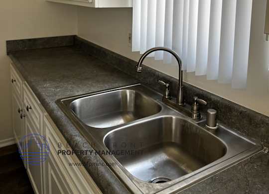 A kitchen with a sink and a window with blinds.