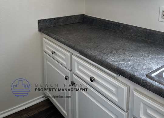 A kitchen with white cabinets and a granite countertop.