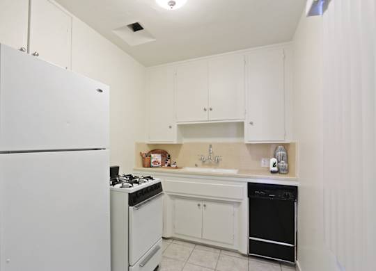 A white kitchen with a refrigerator, stove, and oven.