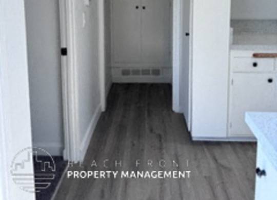 A hallway with a door at the end and a logo for Beach Road Property Management.