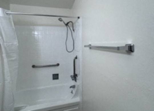 A white bathroom with a toilet, shower and a towel rack.