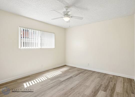 A room with a ceiling fan and a window with blinds.