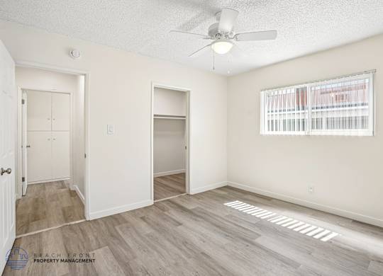 A room with a ceiling fan and a window with blinds.