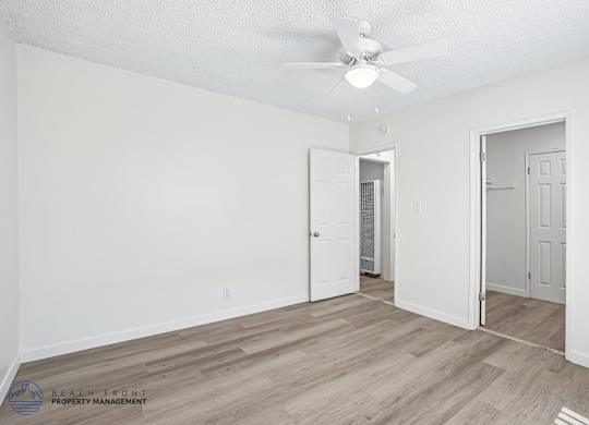 A spacious room with a ceiling fan and wooden flooring.