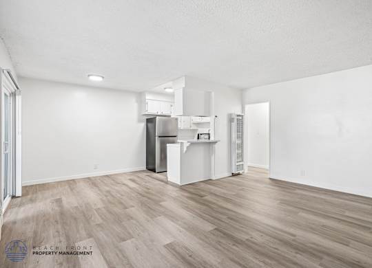 A spacious kitchen with white cabinets and a wooden floor.
