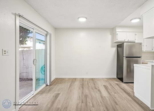 A kitchen with a refrigerator, dishwasher, and cabinets.