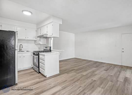 A kitchen with white cabinets and a black refrigerator.