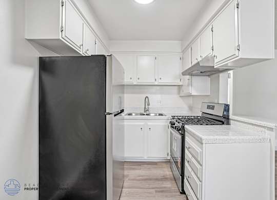 A kitchen with a black refrigerator and white cabinets.