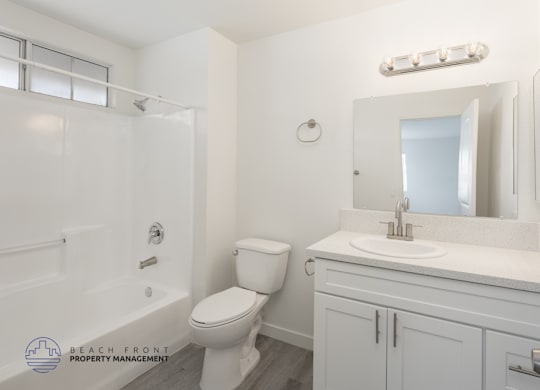 A white bathroom with a toilet, sink, and mirror.