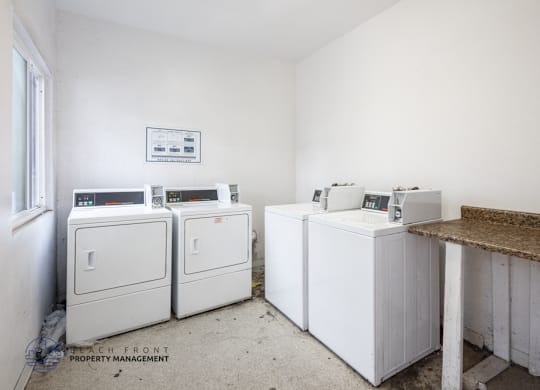 A white room with a brown counter and a fridge on the left.