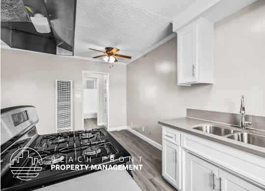 A kitchen with a stove, sink, and cabinets.