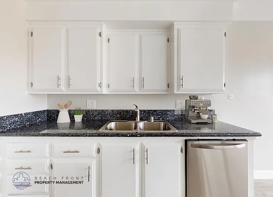 A kitchen with white cabinets and a granite countertop.