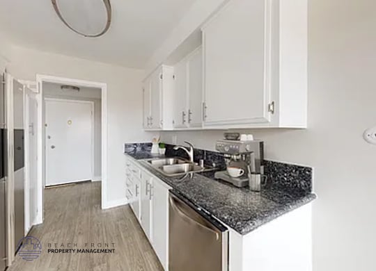 A kitchen with white cabinets and a black counter top.